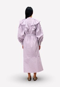 Gestreepte jurk met een getailleerde taille, voorzien van grote volantschouders en lange pofmouwen. De stof is licht met verticale roze en witte strepen.