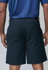 Marineblaue Shorts mit glatter Textur, elastischem Bund und einer Gesäßtasche. Die Länge reicht bis zur Mitte des Oberschenkels und bietet eine lockere Passform.