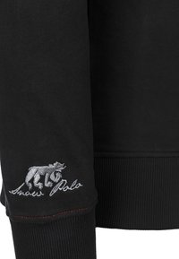 Černá mikina s vyšívaným šedým logem medvěda a nápisem "Andres Polo". Žebrované manžety s jemným červeným prošitím.