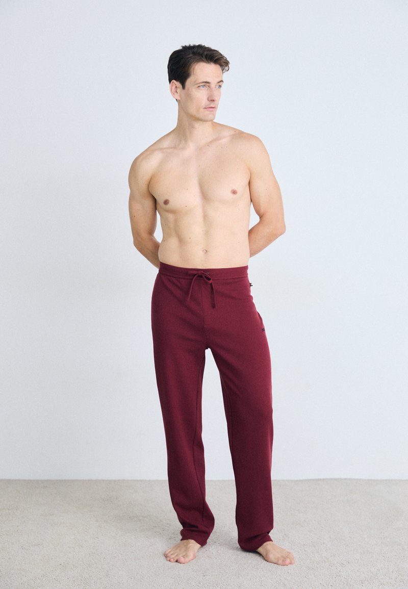Pantalones de lounge burdeos con cintura ajustable, hechos de tela suave, presentan un corte relajado y un diseño limpio sin estampados ni logotipos.