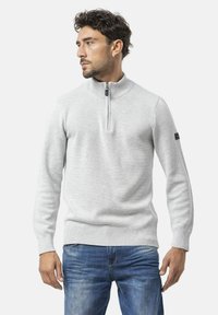 Hellgrauer, gestrickter Pullover mit hohem Kragen und halbem Reißverschluss. Mit gerippten Bündchen und Saum; Logo-Patch auf dem linken Ärmel.