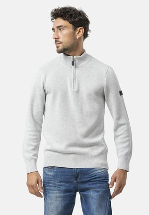 Lichtgrijze, gebreide trui met een hoge kraag en een halve ritssluiting. Voorzien van geribde manchetten en zoom; logopatch op de linkermouw.