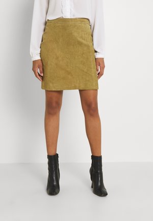 Jupe en daim vert olive au design ajusté, avec une texture lisse et une coupe droite, associée à des bottines noires.