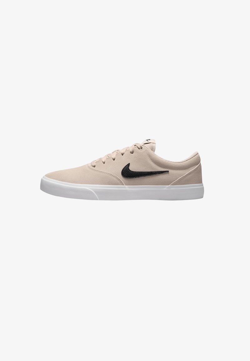 Zapatillas beige de material ante, con suela de goma blanca, swoosh negro en el lateral, punta redonda y seis ojales para los cordones.