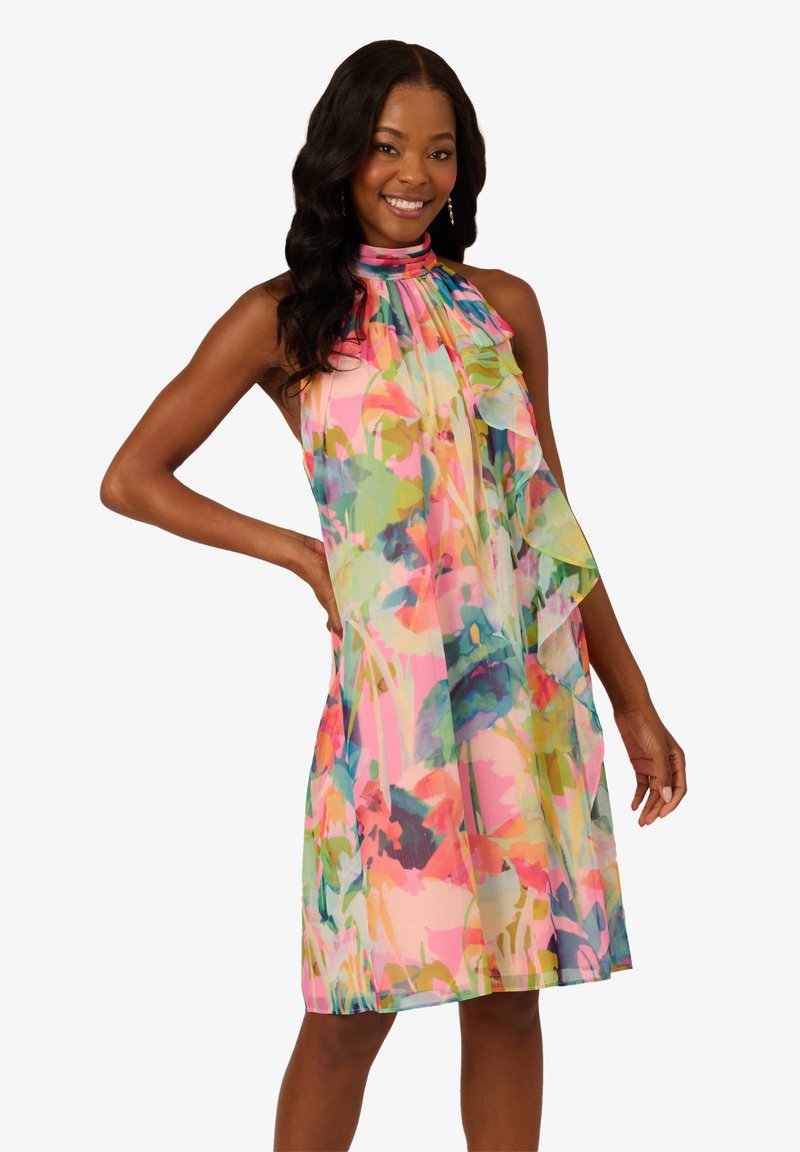 Robe sans manches à motif floral en tissu léger et transparent. Présente un col haut et des teintes colorées de rose, vert et bleu.