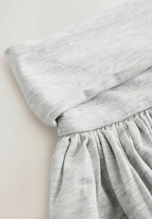 Vaaleanharmaa kangas, jossa taitettu vyötärönauha ja sen alla kerätty, ryppyinen pinta. Pehmeä, sileä materiaali, jossa hienovaraisia värivaihteluita.