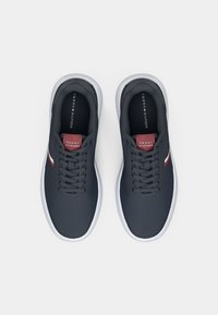 Marineblå sneakers med en glat stofoverdel, hvid gummisål og rød- og hvid akcentstribe på siden. Snørebåndsdesign med mærket indersål.