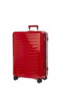 Valigia rigida rossa con scanalature orizzontali, manico retrattile e quattro ruote scorrevoli. Presenta una finitura liscia e lucida.