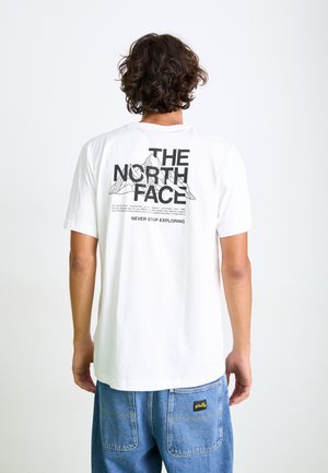 T-shirt en coton blanc avec un design graphique au dos comprenant "THE NORTH FACE" et des silhouettes de montagnes. Manches courtes et coupe décontractée.