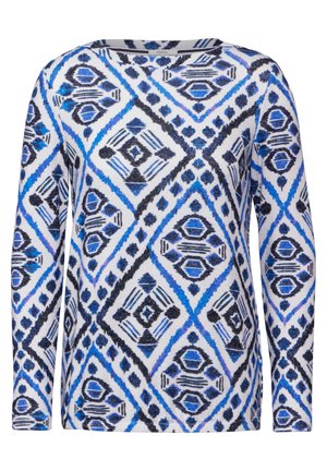 Top à manches longues en tissu blanc arborant un motif géométrique en losange bleu et noir, avec un col rond et une coupe ajustée.