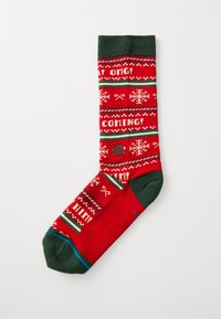 Calcetín rojo con acentos verdes, que presenta patrones de temática invernal, incluyendo copos de nieve y frases en blanco, fabricado con un material suave.