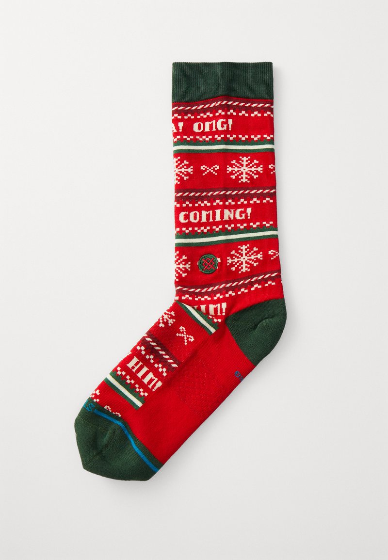 Calcetín rojo con acentos verdes, que presenta patrones de temática invernal, incluyendo copos de nieve y frases en blanco, fabricado con un material suave.
