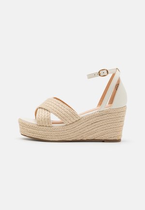 Beige vævet kilehøjhælet sandal med ankelrem og spænde, med flettet rebtekstur på platåsål og åben tå-design.