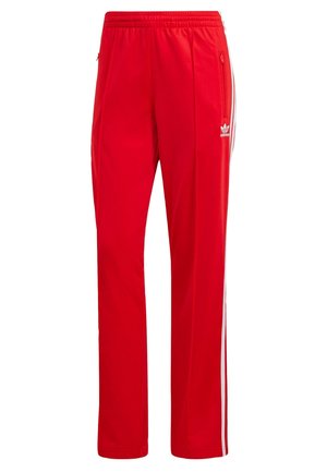 Pantaloni sportivi rossi in poliestere, con strisce bianche laterali e un cinturino elastico in vita. Include tasche con zip per riporre gli oggetti.