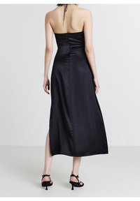 Robe maxi en satin noir avec un corsage ajusté, des détails froncés et une fente latérale, avec un design sans bretelles et une fermeture à l'arrière.