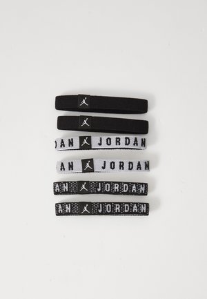 Set von sechs elastischen Haargummis in Schwarz und Weiß. Schwarze Gummis mit Logo, zwei gestreifte Gummis mit dem Text "JORDAN", verschiedene Texturen und Stärken.
