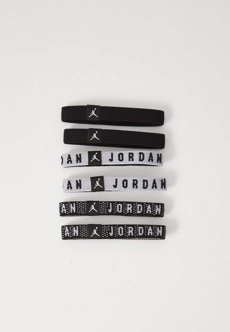 Σετ από έξι ελαστικές κορδέλες μαλλιών σε μαύρο και άσπρο. Μαύρες κορδέλες με λογότυπο, δύο ρίγες με το κείμενο "JORDAN", διάφορες υφές και πάχη.