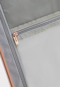 Interno della valigia in tessuto grigio con tasca in rete con zip e tirazip in metallo color rame rosa inciso con la scritta "WITTCHEN."
