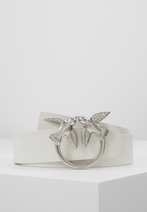Weißer Ledergürtel mit einer silbernen Schnalle, die zwei detaillierte Vögel zeigt, die sich gegenüber auf einem runden Ring befinden.