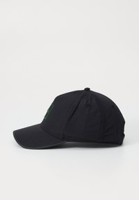 Black baseball cap with a rounded crown and a rigid visor. Features a green logo patch on the front and button accent on the crown.