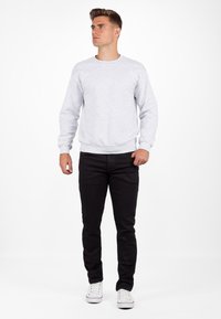 Grijze sweatshirt met ronde hals en lange mouwen, gecombineerd met zwarte broek en witte sneakers. Eenvoudig, casual ontwerp zonder zichtbare patronen.