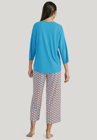 Blauw, lang mouwtop met een ronde hals, gecombineerd met losse, gestreepte broek met verticale strepen en bloemenaccenten.