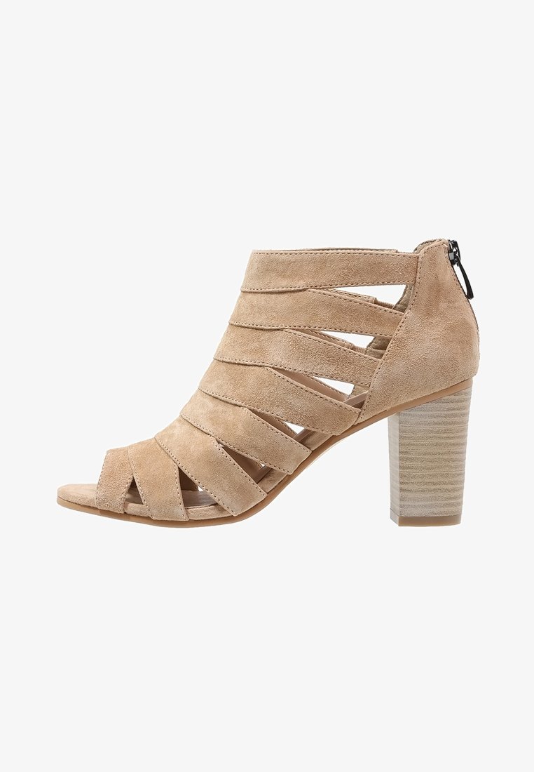 Sandale ouverte à bout ouvert en daim beige avec talon bloc empilé et plusieurs brides horizontales couvrant le pied, fermeture éclair arrière.