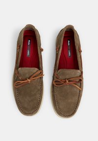 Pruunist sametist loafers, ümarate varvastega, nahkpaeltega, beežide kummist talladega ja punaste sisetaldadega, millel on õmblustähtsus.
