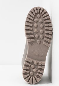 Botte en daim gris avec une semelle extérieure en caoutchouc texturée présentant des motifs hexagonaux et des rainures profondes pour l'adhérence. Logo imprimé sur la semelle.