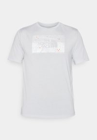 Vit kortärmad t-shirt i bomull med en texturerad grafisk design i grått och orange, med "The North Face"-logotypen tydligt synlig.