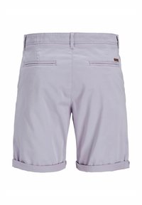 Shorts lavande clair avec une texture lisse, dotés de deux poches arrière et d'un revers. Détail de branding subtil près de la taille.