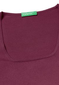 Lila Strickoberteil mit quadratischem Ausschnitt und grünem "United Colors of Benetton"-Label am Kragen.