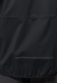 Giacca impermeabile nera con una texture liscia, orlo elastico e una striscia riflettente orizzontale nella parte inferiore per una maggiore visibilità.