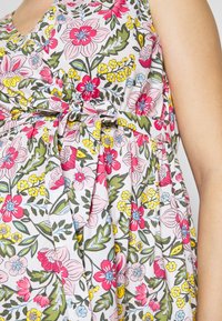 Vestido de estampado floral con flores rosas, rojas, amarillas y verdes sobre un fondo claro. Presenta un escote en V y tejido fruncido con una cintura atada.