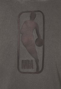 Grauem Stoff mit einem strukturierten NBA-Logo, das einen Spieler in Bewegung darstellt, umgeben von einem erhabenen Rand und fettem Schriftzug darunter.