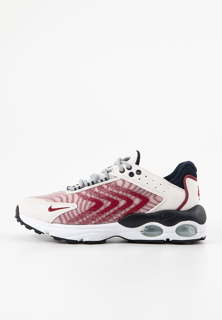 Scarpa sportiva rossa e bianca con tomaia in rete, motivo a zig-zag, dettagli neri e ammortizzazione d'aria trasparente nella suola. Chiusura con lacci.