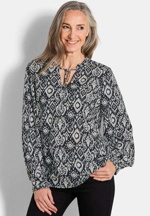 Langärmlige Bluse in Marineblau mit weißen geometrischen Mustern, leichtes Material, gespaltene Halslinie mit Bindeband, elastische Manschetten.
