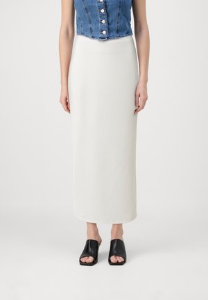 Vit ribbade kjol med rak silhuett, kombinerad med en denimcroppad topp med silverfärgade knappar och svarta öppetåiga mules.