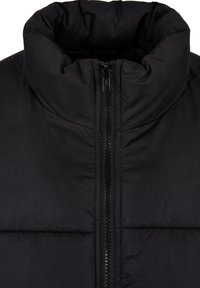 Chaqueta acolchada negra con cuello alto, cierre frontal de cremallera, textura suave y paneles acolchados para aislamiento.