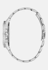 Srebrny zegarek metalowy z okrągłą tarczą, teksturowanym pierścieniem i połączonym bransoletem z bezpiecznym zapięciem. Starannie wypolerowana powierzchnia i subtelne detale.