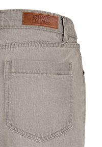 Pantalones de mezclilla color gris claro que cuentan con un bolsillo trasero y una etiqueta de cuero marrón con la inscripción "Urban Classics Denim Factory" en relieve.