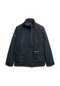 Marineblauwe geïsoleerde jas met hoge kraag, twee voorzakken en ritszakken op de borst. Kenmerkt logo-details in lichtgoud.