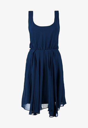 Vestido sin mangas de color azul marino con cintura ceñida y falda fluida, confeccionado en tela liviana, combinado con tacones altos en color nude.