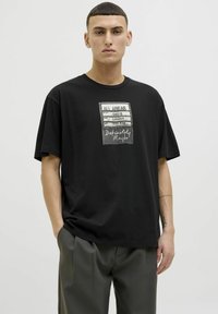 Black cotton t-shirt featuring a graphic print of concert details on the front. Relaxed fit with short sleeves and a round neckline.