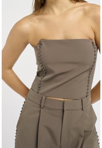 Top taupe senza spalline con dettagli in metallo, indossato con pantaloni a vita alta abbinati, mostrato dalle spalle ai fianchi.