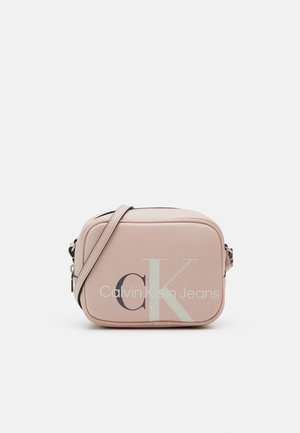 Petit sac bandoulière rectangulaire rose pâle avec sangle réglable et grand logo "cK Calvin Klein Jeans" sur le devant.