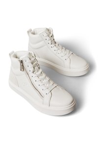 Pāris baltu augstpārvalku ādas sporta apavu ar šņorēm un sānu rāvējslēdzēju, novietoti uz balta virsmas ar ēnām.