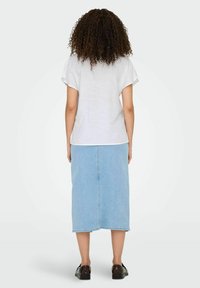 Biała bluzka krótki rękaw w połączeniu z jasnoniebieską spódnicą midi z dżinsu. Gładki materiał i casualowy styl. Czarne buty dopełniają całość.