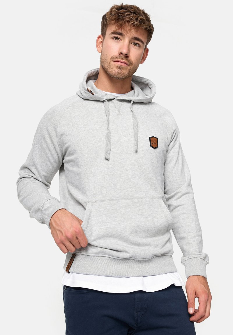 Felpa grigia in morbido tessuto con tasca a marsupio, cappuccio regolabile con cordino e un piccolo patch logo marrone sul petto.