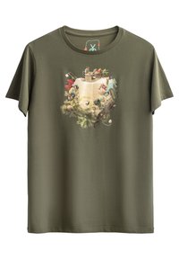 T-shirt in cotone verde oliva con una stampa grafica colorata di un paesaggio contenente vari personaggi e oggetti disposti in un formato circolare.
